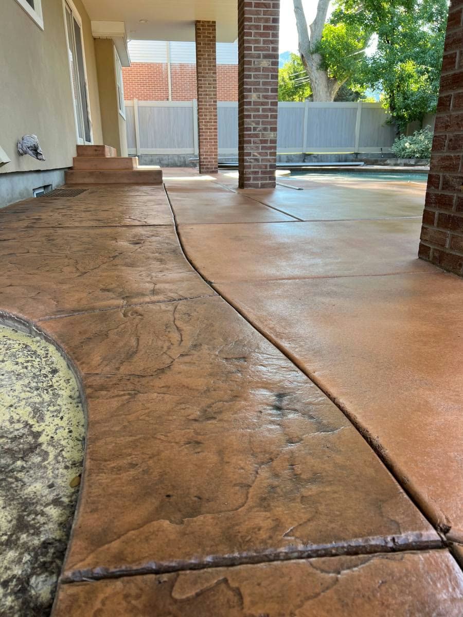 Finished stamped and colored concrete patio surrounding a backyard pool