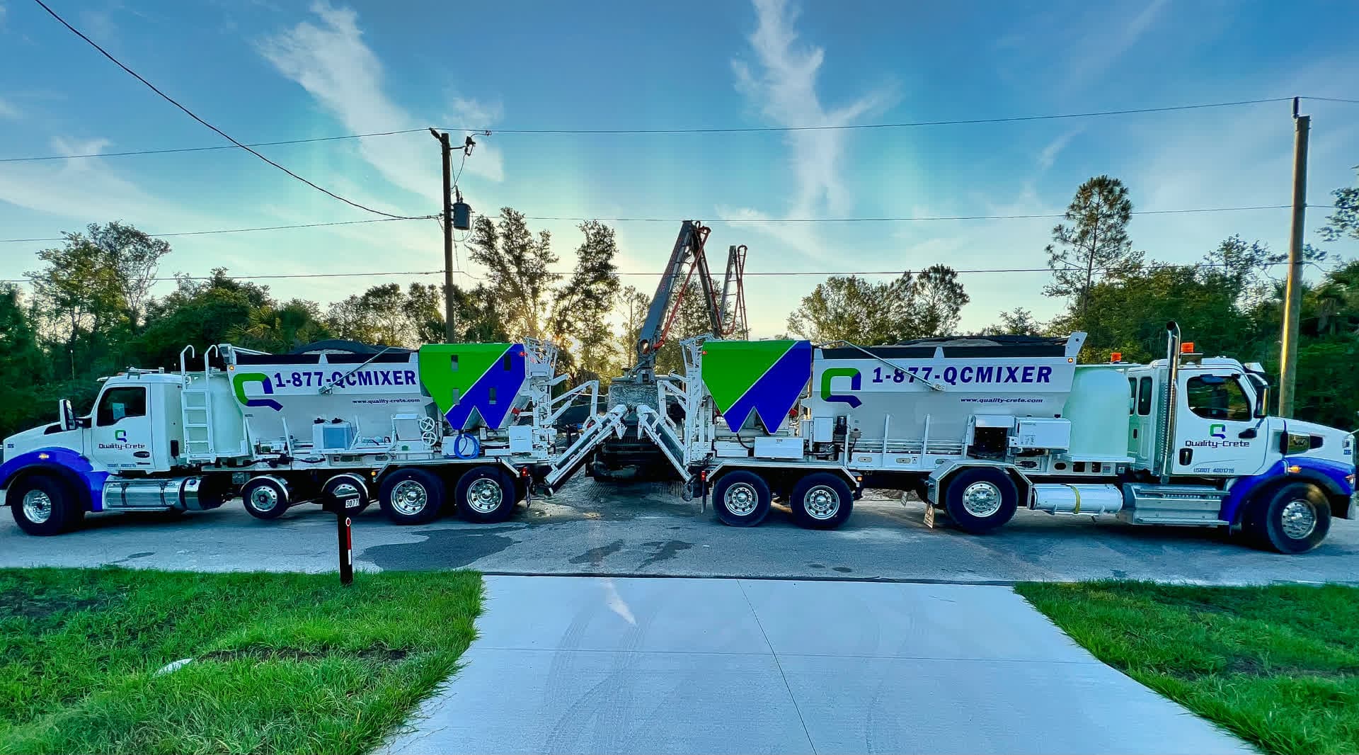 Two Quality-Crete volumetric mixer trucks parked either side of a finished concrete driveway