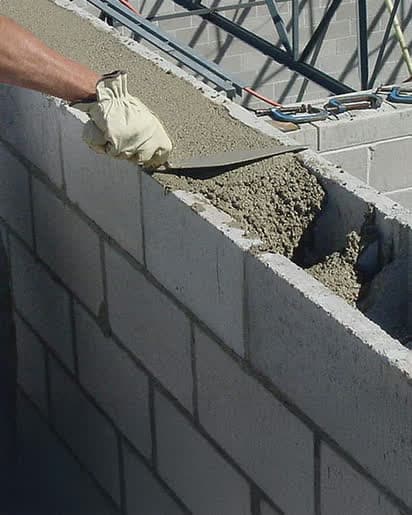 Concrete being trowelled into the cores of a block wall