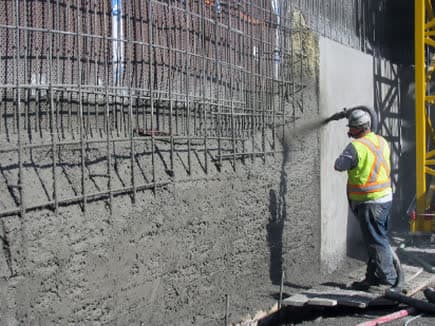 Shotcrete being sprayed onto a reinforced vertical wall