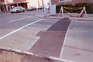 Utility cut repaired with a fresh asphalt patch in a parking lot
