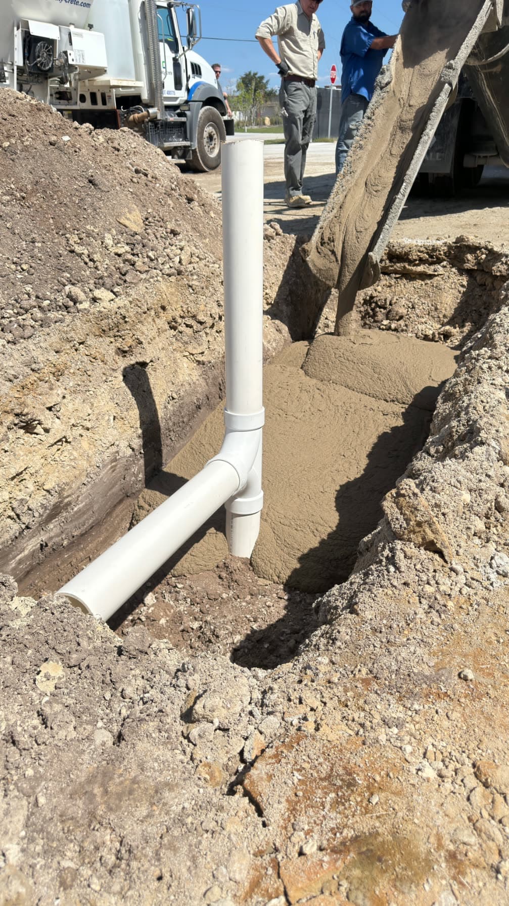 Fast setting flowable fill being discharged into a trench