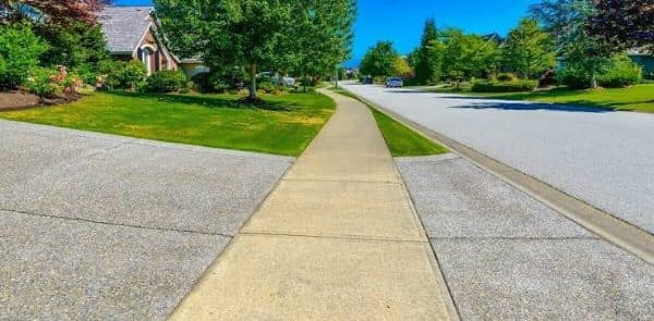 New concrete sidewalk through a green lawn