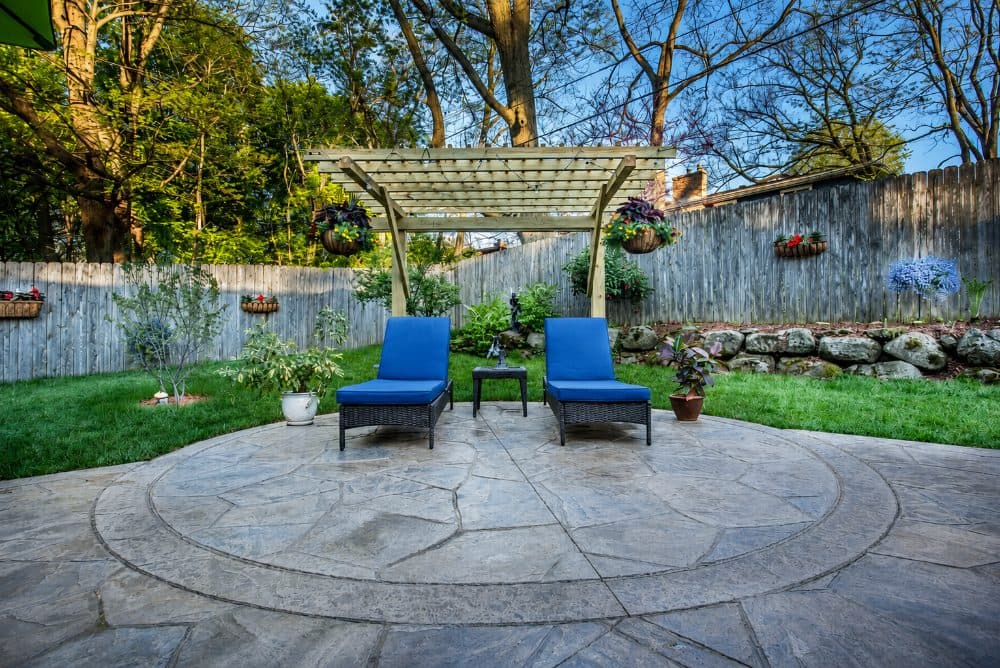 Stamped concrete patio with lounge chairs under a pergola